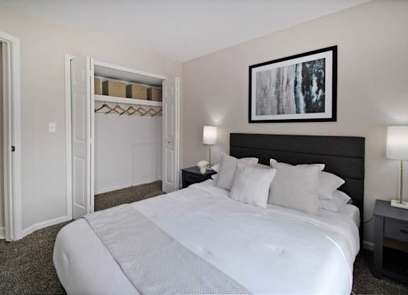 A bedroom with a large bed and a painting on the wall.