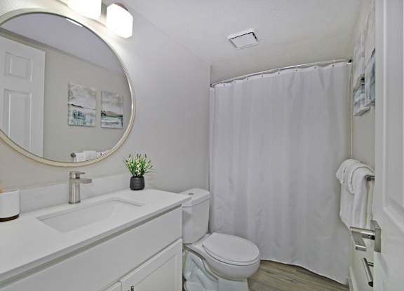 A white bathroom with a toilet, sink, and shower.