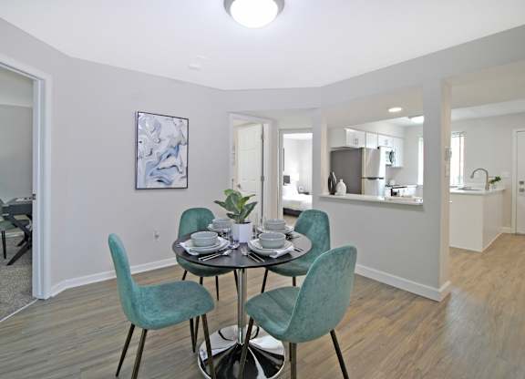 A dining room with a table set for two and a painting on the wall.