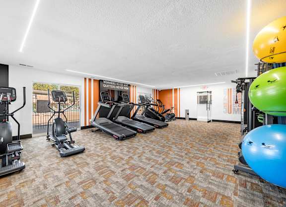 A gym with a variety of equipment including treadmills, stationary bikes, and weight machines.