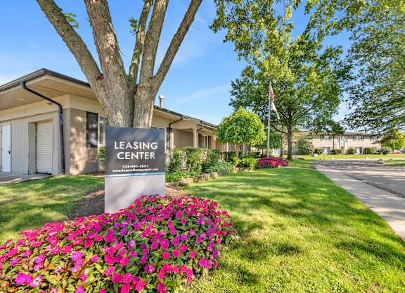 A sign for Cambridge on Ford Apartments is displayed in front of a landscaped area.