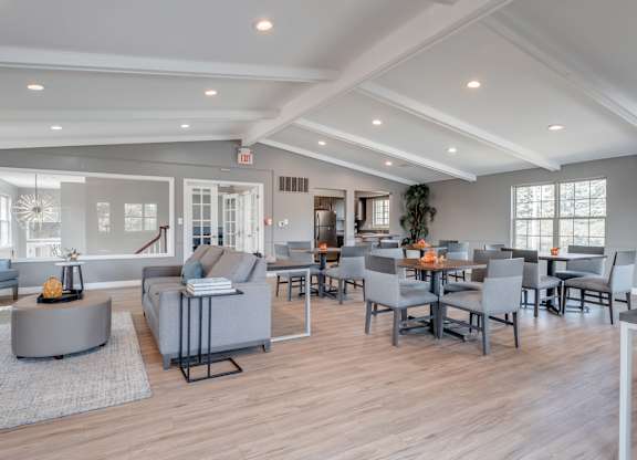A spacious living room with grey furniture and a wooden floor.