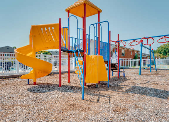 A playground with a yellow slide and blue and red structures.