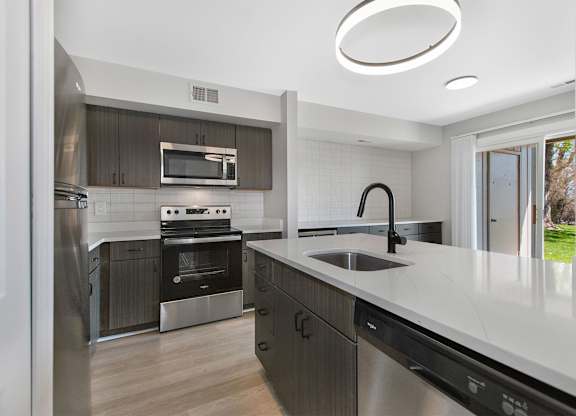 A modern kitchen with a stainless steel refrigerator, oven, and sink.