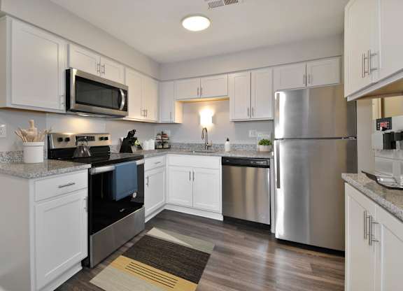 A kitchen with white cabinets and a stainless steel refrigerator.