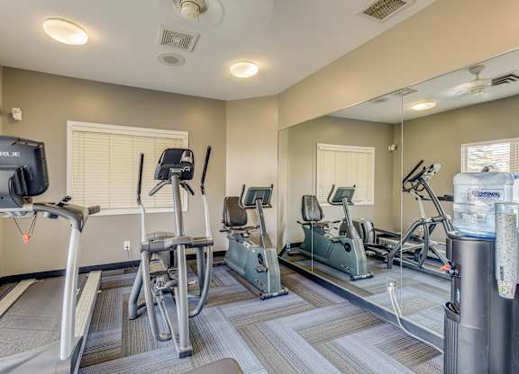 A gym with treadmills, exercise bikes, and a television.