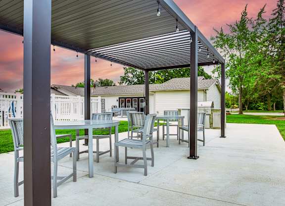 A patio with a table and chairs under a roof.