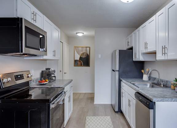 A kitchen with black appliances and white cabinets.