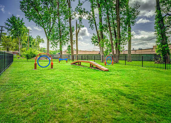 A playground with a green lawn and a black fence.
