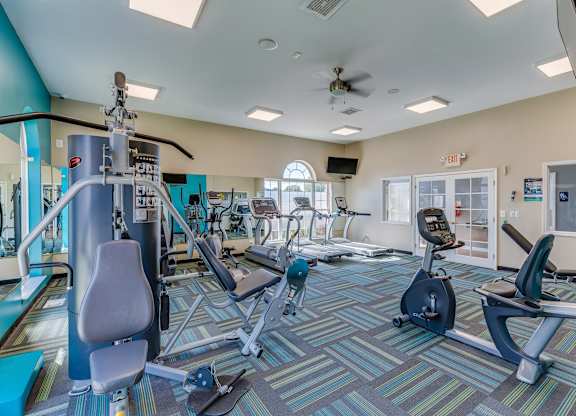 A gym with a variety of equipment including treadmills, stationary bikes, weights, and exercise machines.