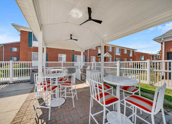 A patio with a white canopy and red and white striped chairs.
