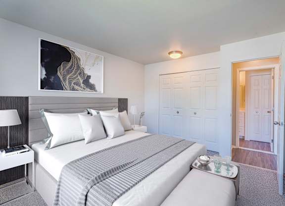 A bedroom with a large bed and a painting on the wall.
