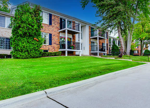A row of apartment buildings with green lawns in front.