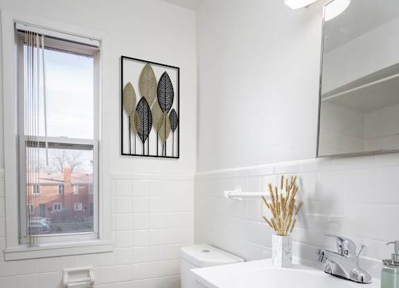 A white bathroom with a toilet, sink, and mirror.