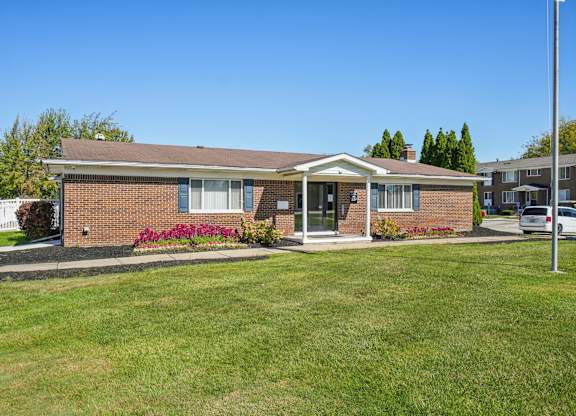 A small brick house with a front porch and a green lawn.