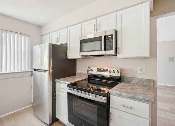 A kitchen with a stove, oven, refrigerator, and microwave.