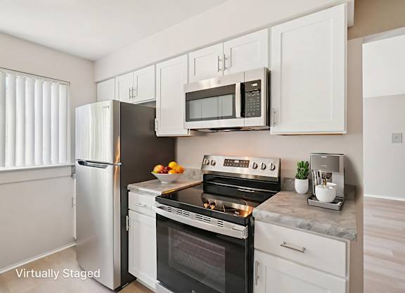 A kitchen with a stove, oven, refrigerator, and microwave.