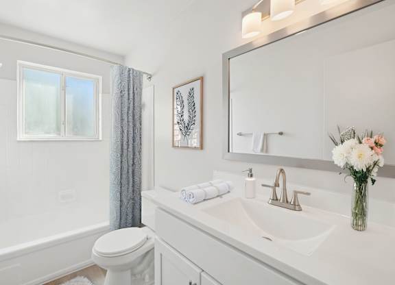 A white bathroom with a toilet, sink, and bathtub.