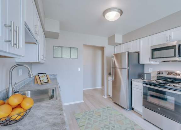 A kitchen with white cabinets and a stainless steel refrigerator.