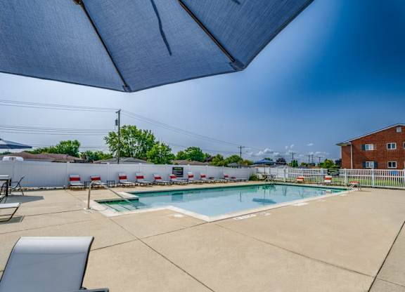 A pool area with a blue umbrella and a white fence.