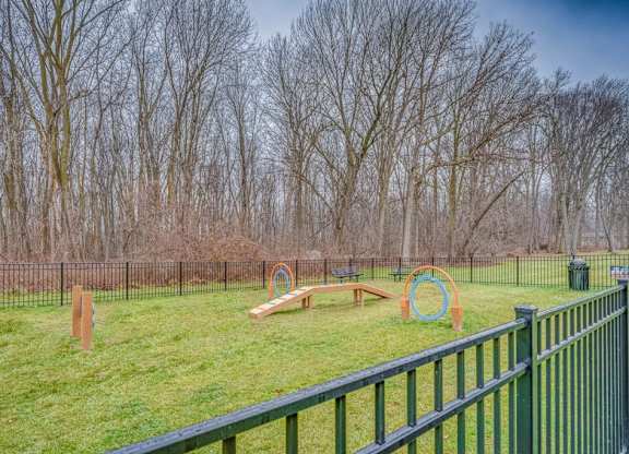 A playground with a green fence and a swing set.