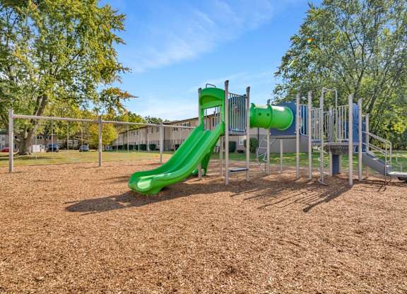 A playground with a green slide and a climbing frame.