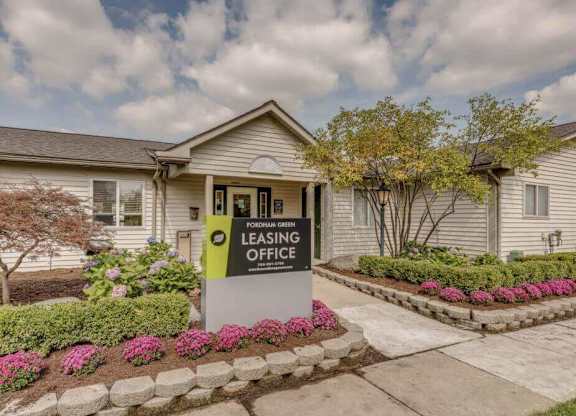 A sign for a leasing office is in front of a house.