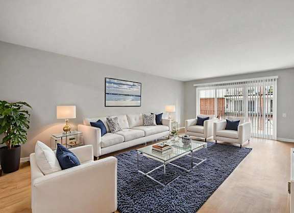 A living room with a white couch, a coffee table, and a large window.