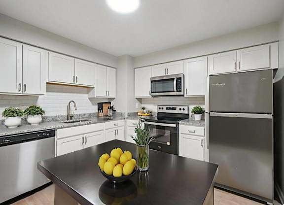 A kitchen with a black countertop and stainless steel appliances.