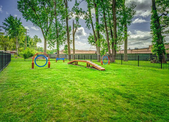 A playground with a green lawn and a black fence.