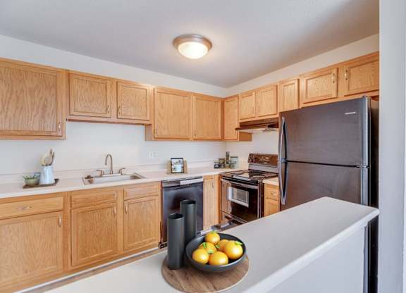 A kitchen with wooden cabinets and a black refrigerator.