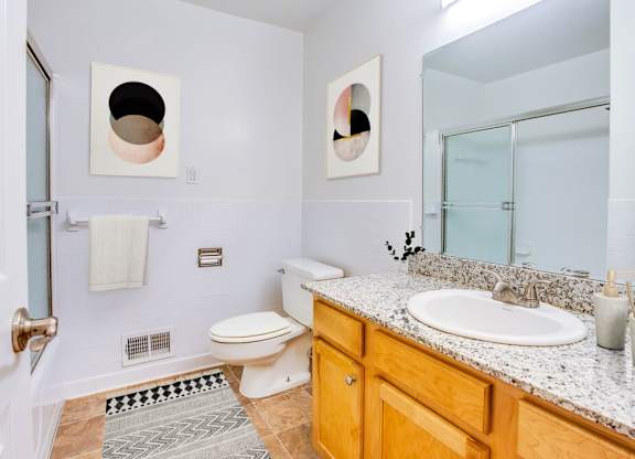 A bathroom with a toilet, sink, and mirror.