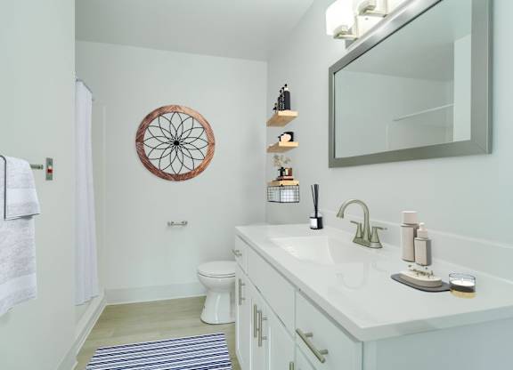 A bathroom with a white counter top and a round mirror on the wall.