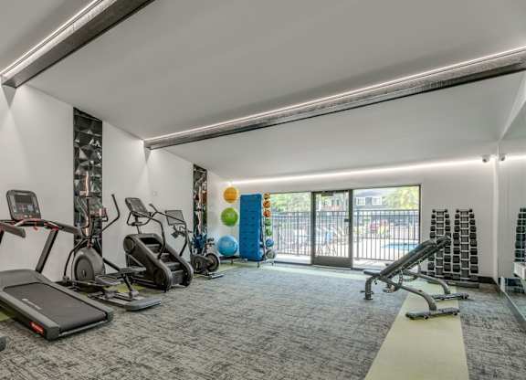 A gym with treadmills, elliptical machines, and other exercise equipment.
