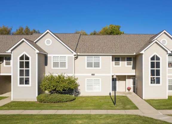 A large, two-story residential building with a lawn in front.