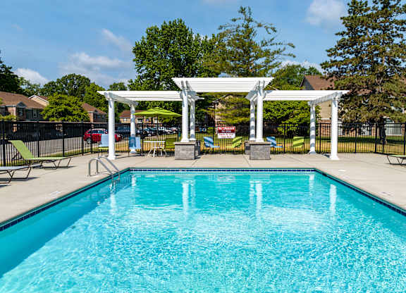 A pool with a white pergola over it.