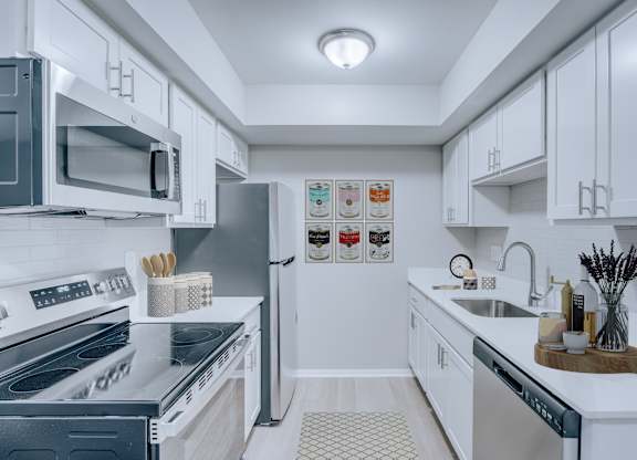 A modern kitchen with white cabinets and stainless steel appliances.