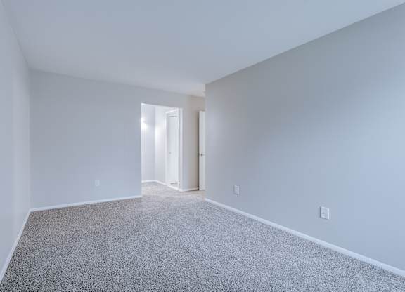 A room with a carpeted floor and a doorway leading to another room.