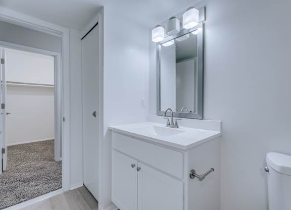 A white bathroom vanity with a mirror above it.