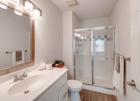 A white bathroom with a sink, toilet, and shower.
