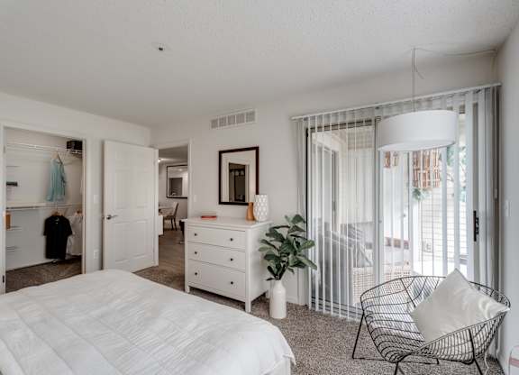 A white bedroom with a large bed and a chair.