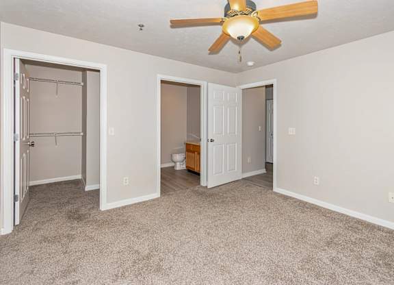 A room with a ceiling fan and a doorway leading to another room.