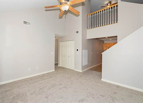 A room with a ceiling fan and a staircase.
