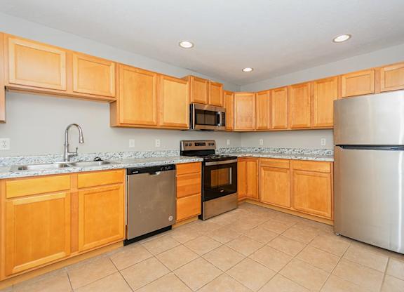 A kitchen with wooden cabinets and a stainless steel refrigerator.