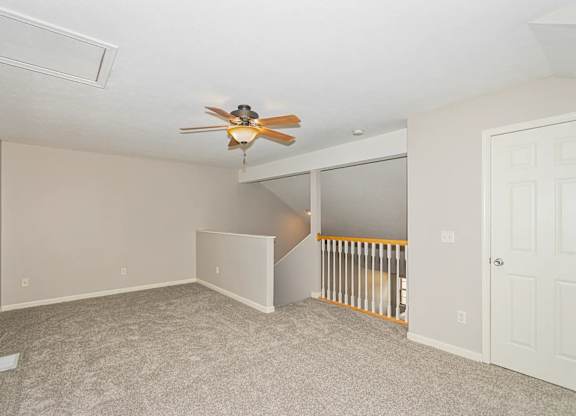 A room with a ceiling fan and carpeted floor.