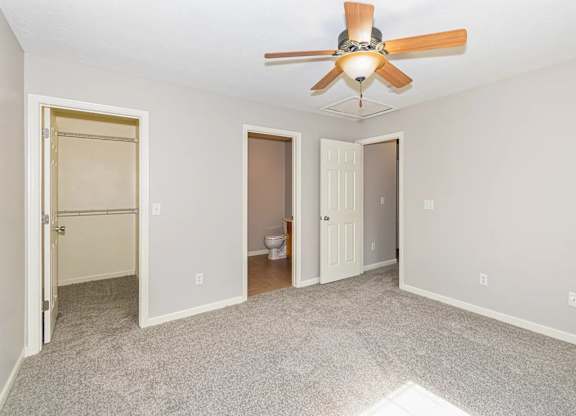 A room with a ceiling fan and carpeted floor.