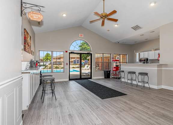 A spacious room with a bar area and a view of a pool through an arched window.