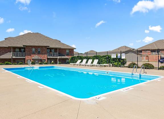 A large swimming pool in front of a building with a fence around it.