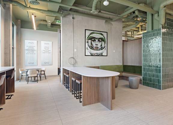 A modern office space with a white reception desk and a green glass partition.