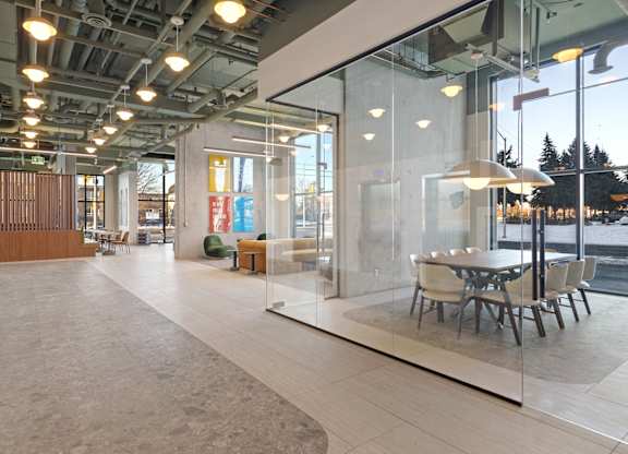 A modern office space with glass walls and a long table with chairs.